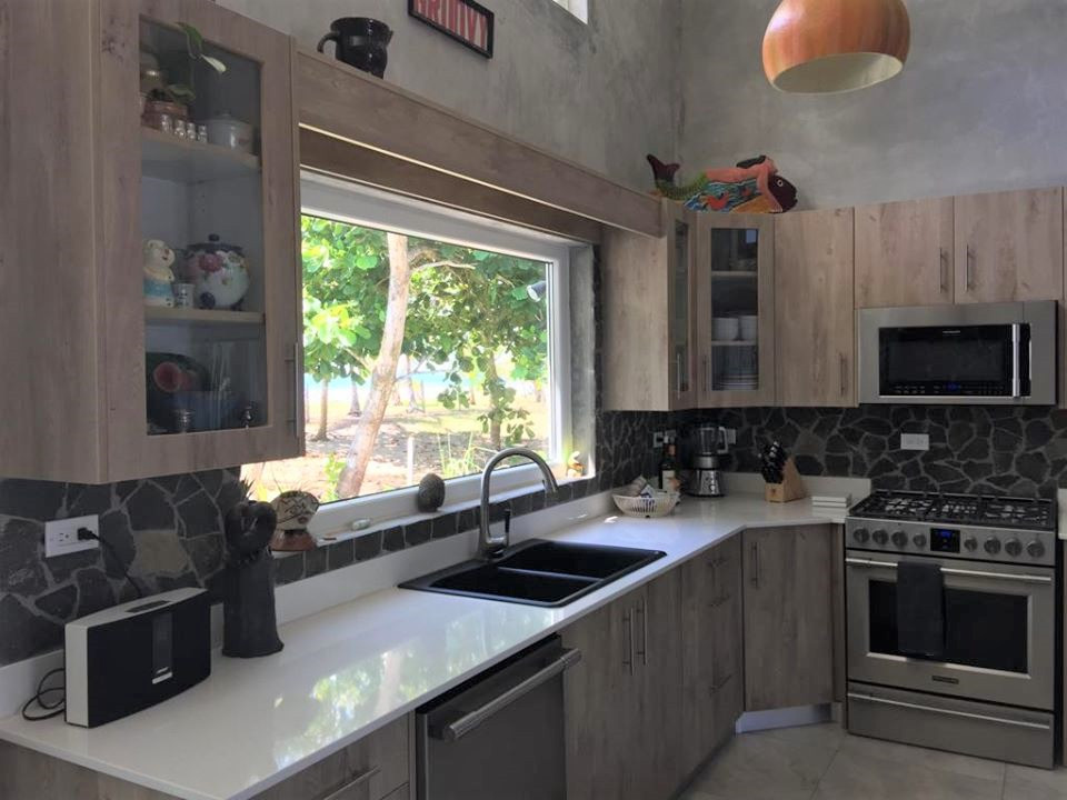 This is an example of a mid-sized country l-shaped eat-in kitchen in Other with a drop-in sink, flat-panel cabinets, light wood cabinets, quartzite benchtops, brown splashback, stone tile splashback, stainless steel appliances, porcelain floors, brown floor, white benchtop and vaulted.