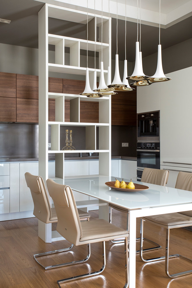 This is an example of a contemporary kitchen/dining combo in Moscow with grey walls and light hardwood floors.