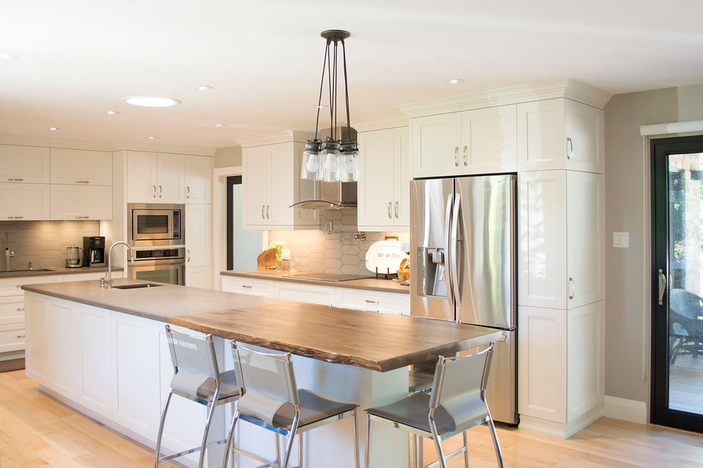 Inspiration for a large transitional light wood floor open concept kitchen remodel with an undermount sink, shaker cabinets, white cabinets, wood countertops, gray backsplash, porcelain backsplash, stainless steel appliances and an island