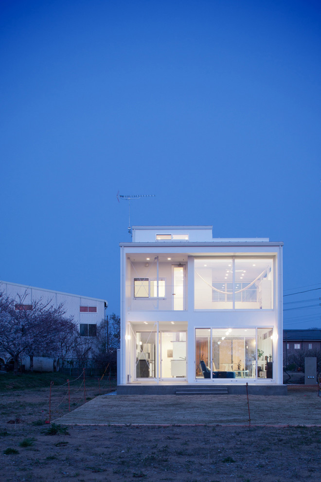 Design ideas for a contemporary two-storey white house exterior in Other with a flat roof.