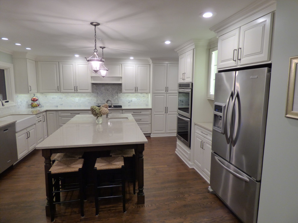 Large transitional u-shaped dark wood floor eat-in kitchen photo in Chicago with a farmhouse sink, raised-panel cabinets, white cabinets, quartz countertops, gray backsplash, stone tile backsplash, stainless steel appliances and an island