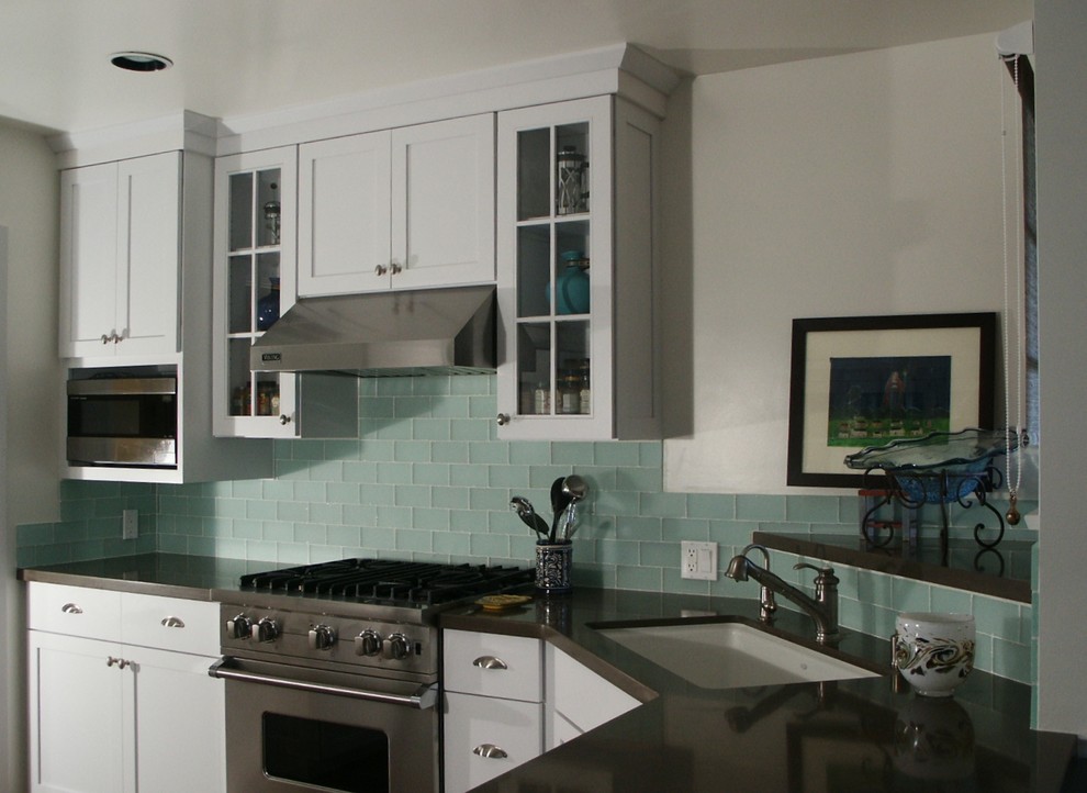 This is an example of a mid-sized eclectic u-shaped eat-in kitchen in Los Angeles with an undermount sink, shaker cabinets, white cabinets, quartz benchtops, green splashback, glass tile splashback, porcelain floors, no island and stainless steel appliances.