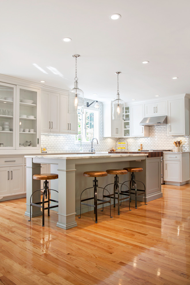 Photo of a traditional kitchen in Boston with shaker cabinets, white cabinets, white splashback, subway tile splashback and stainless steel appliances.