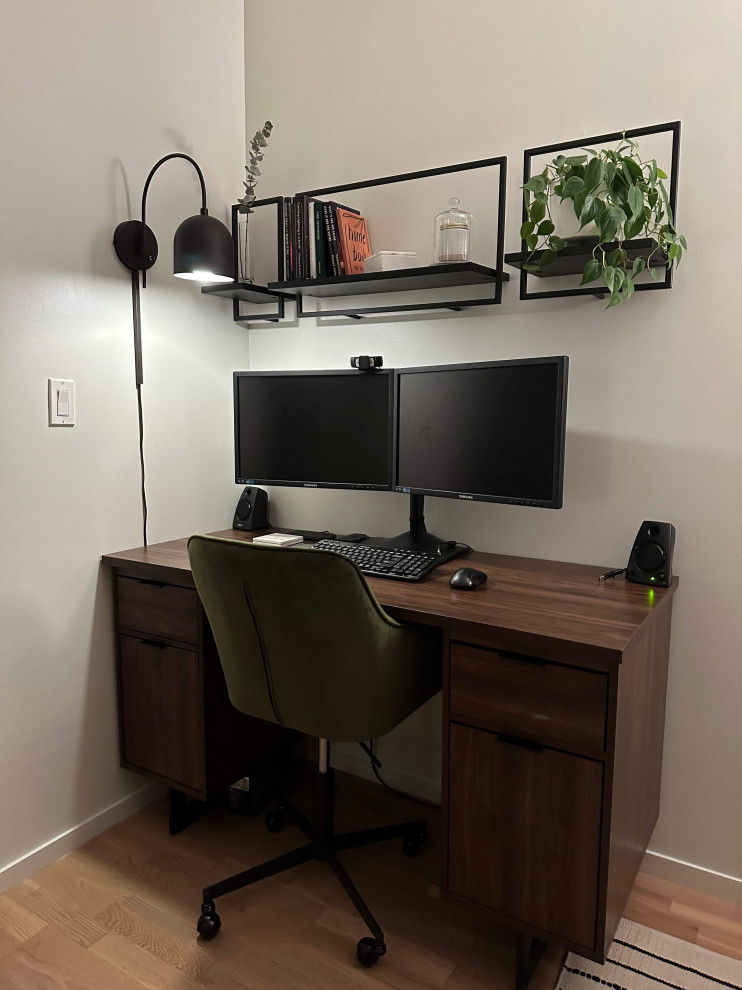 Modelo de despacho urbano pequeño sin chimenea con paredes blancas, suelo de madera clara, escritorio independiente y suelo marrón