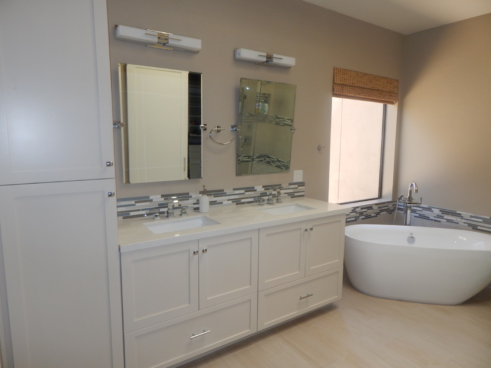 This is an example of a mid-sized contemporary master bathroom in Minneapolis with shaker cabinets, white cabinets, a freestanding tub, a two-piece toilet, multi-coloured tile, porcelain tile, beige walls, porcelain floors, an undermount sink and engineered quartz benchtops.