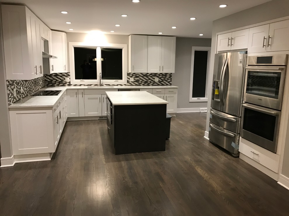 Large modern u-shaped eat-in kitchen in Chicago with an undermount sink, shaker cabinets, white cabinets, quartzite benchtops, brown splashback, glass tile splashback, stainless steel appliances, dark hardwood floors, with island and brown floor.
