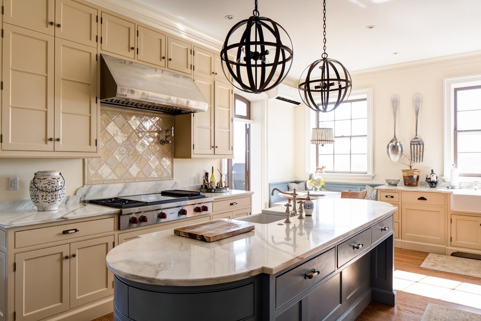 Mid-sized traditional u-shaped separate kitchen in Charleston with a farmhouse sink, beaded inset cabinets, beige cabinets, marble benchtops, stainless steel appliances, medium hardwood floors, with island and brown floor.