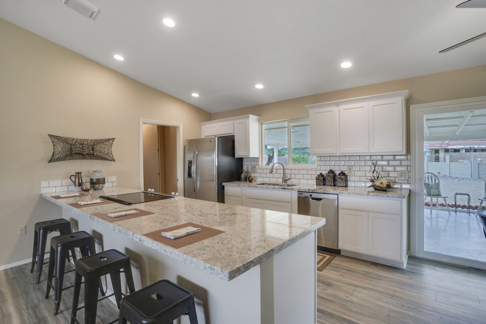 Inspiration for a small transitional single-wall laminate floor and beige floor open concept kitchen remodel in Phoenix with an undermount sink, shaker cabinets, white cabinets, granite countertops, white backsplash, subway tile backsplash, stainless steel appliances, a peninsula and gray countertops