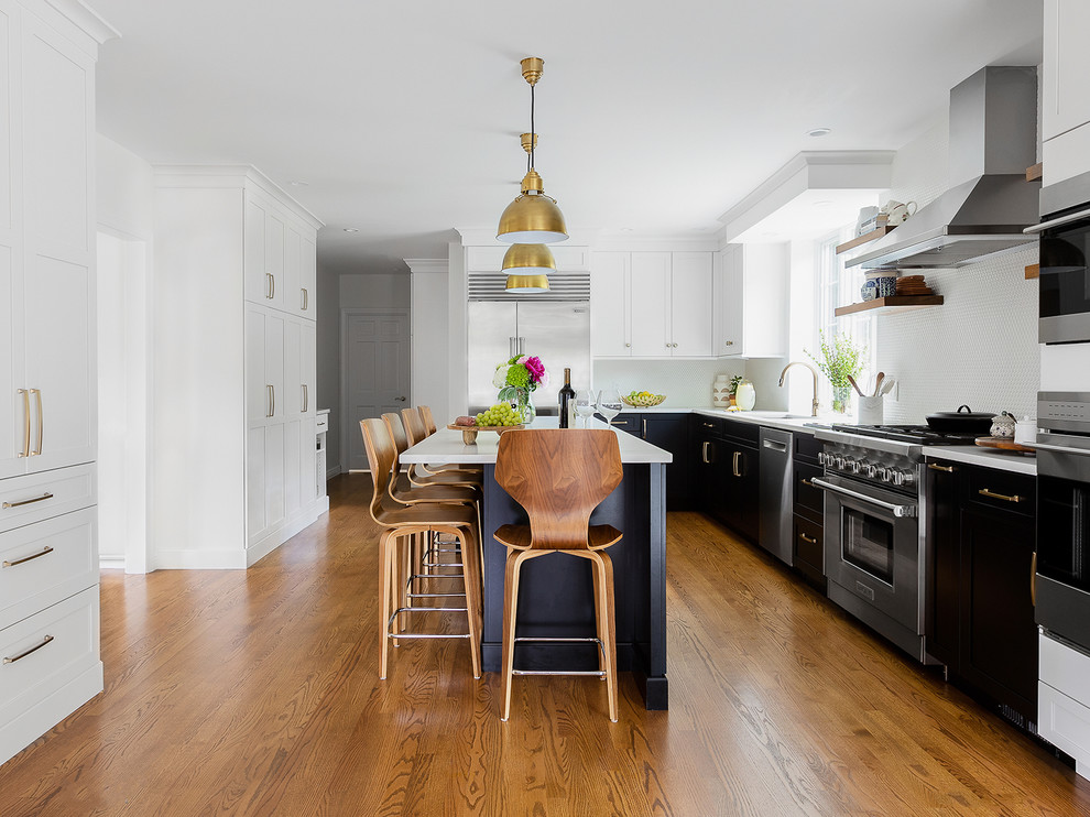 Transitional l-shaped medium tone wood floor kitchen photo with an undermount sink, quartzite countertops, stainless steel appliances, an island, shaker cabinets, white backsplash and white countertops