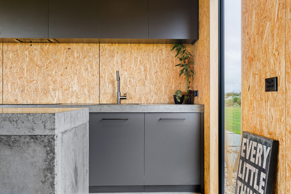 Medium sized industrial kitchen with black cabinets, concrete worktops, wood splashback and grey worktops.