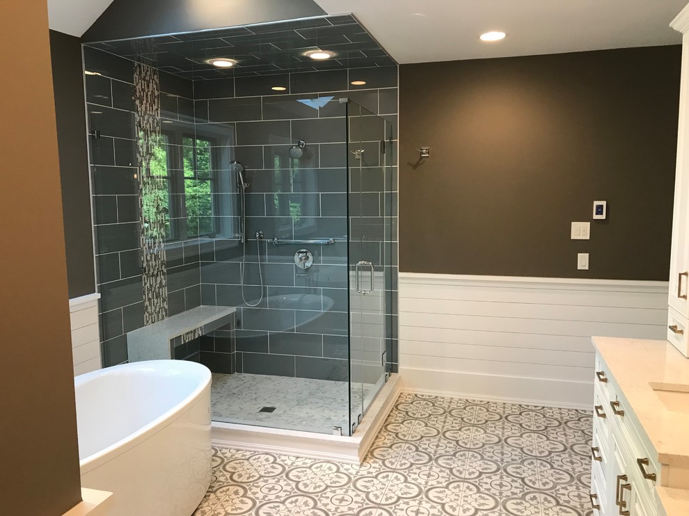 Inspiration for a mid-sized contemporary master bathroom in New York with raised-panel cabinets, white cabinets, a freestanding tub, a corner shower, gray tile, porcelain tile, brown walls, ceramic floors, an undermount sink, multi-coloured floor, a hinged shower door and beige benchtops.