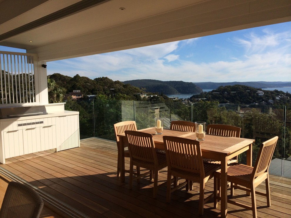 Large beach style deck in Sydney with an outdoor kitchen and a roof extension.