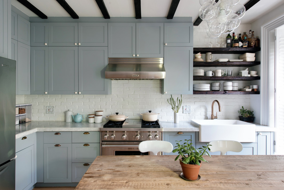 Inspiration for a small transitional l-shaped eat-in kitchen in New York with a drop-in sink, shaker cabinets, grey cabinets, wood benchtops, white splashback, brick splashback, stainless steel appliances, with island, white benchtop, exposed beam, medium hardwood floors and brown floor.