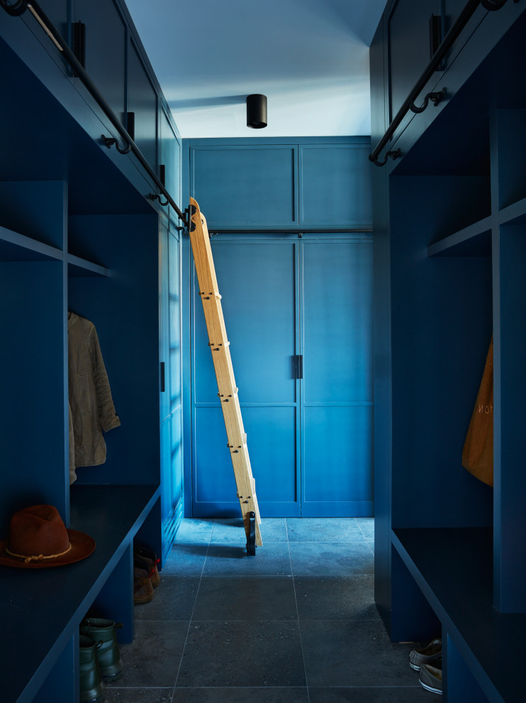 Photo of a large eclectic storage and wardrobe in New York with blue cabinets, limestone floors and black floor.