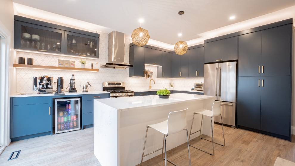 Minimalist l-shaped vinyl floor and beige floor open concept kitchen photo in Toronto with flat-panel cabinets, blue cabinets, quartz countertops, an island, white backsplash, cement tile backsplash, stainless steel appliances and white countertops