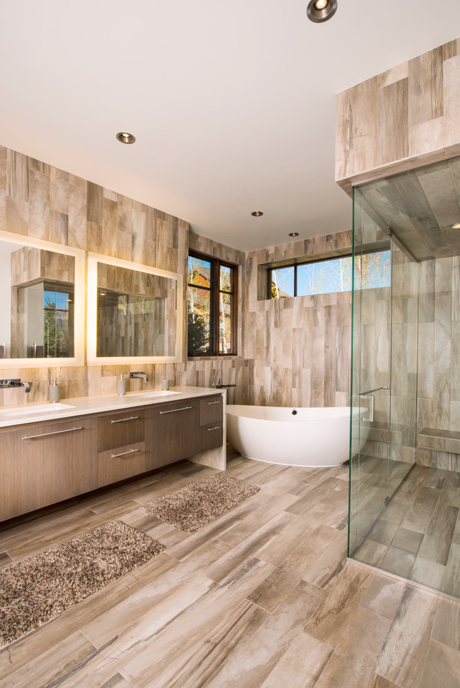 This is an example of a large contemporary master bathroom in Denver with flat-panel cabinets, dark wood cabinets, a freestanding tub, a curbless shower, brown tile, an undermount sink, marble benchtops, porcelain tile, grey walls, porcelain floors, brown floor and an open shower.