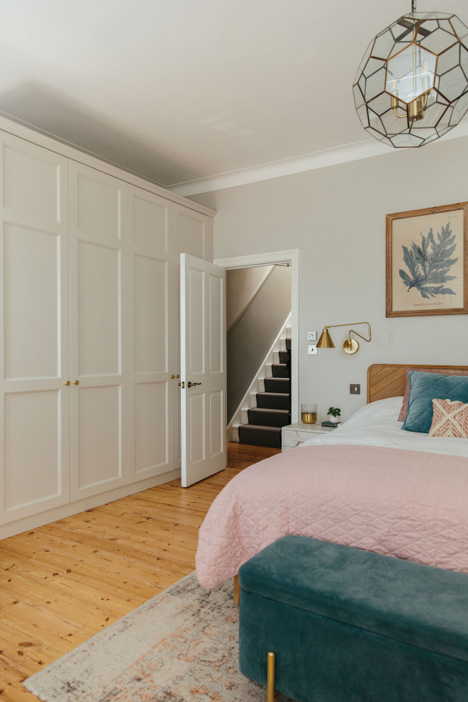 Photo of a large classic master bedroom in London with beige walls, medium hardwood flooring, a standard fireplace, a tiled fireplace surround, beige floors and a chimney breast.