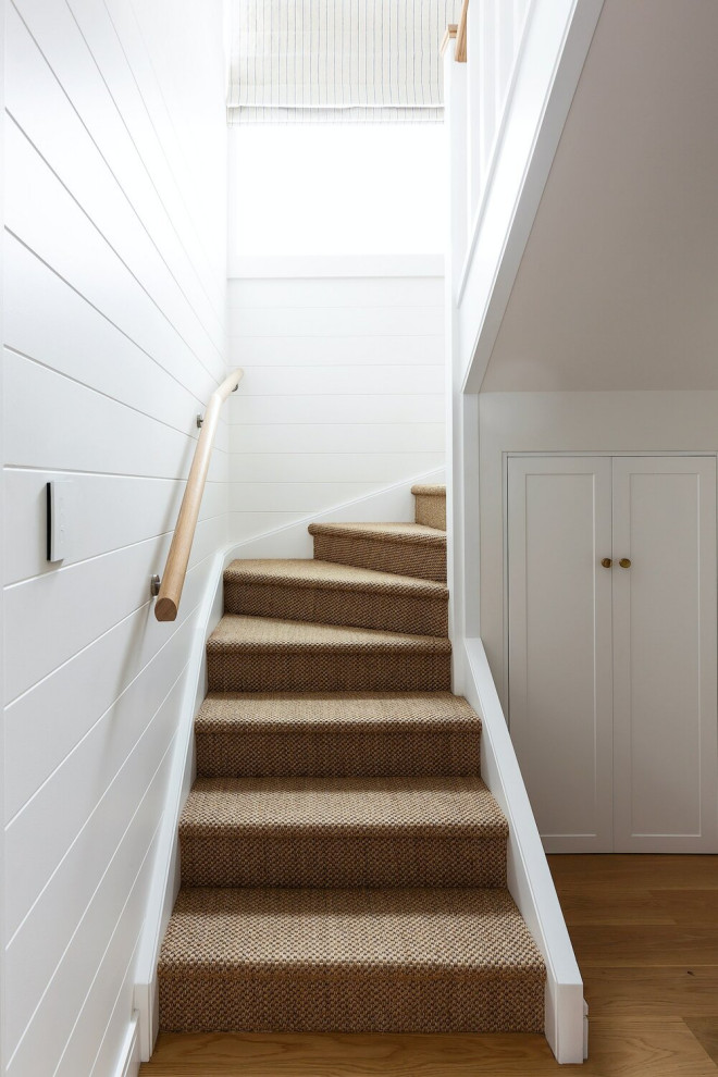 Inspiration for a mid-sized beach style carpeted u-shaped staircase in Sydney with carpet risers, wood railing and planked wall panelling.