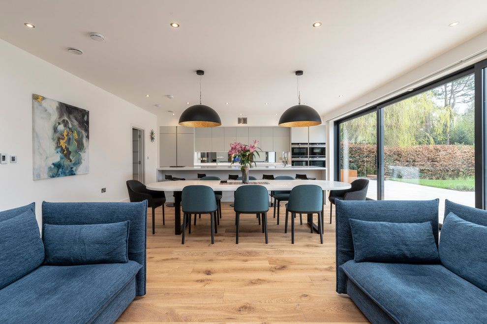 Photo of a contemporary open plan dining in Cheshire with white walls, medium hardwood floors and brown floor.