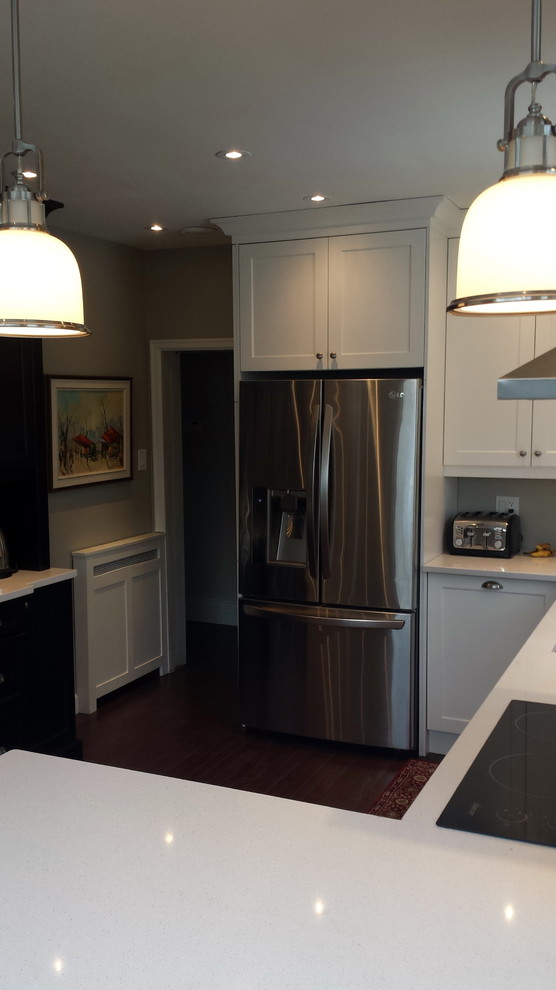 Mid-sized transitional u-shaped dark wood floor enclosed kitchen photo in Ottawa with an undermount sink, shaker cabinets, white cabinets, quartz countertops, white backsplash, subway tile backsplash, stainless steel appliances and a peninsula