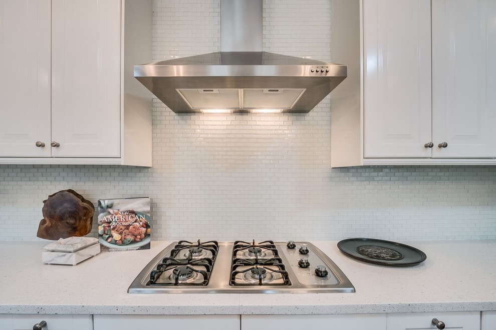 Mid-sized transitional u-shaped medium tone wood floor and brown floor open concept kitchen photo in Phoenix with raised-panel cabinets, white cabinets, quartz countertops, white backsplash, matchstick tile backsplash, stainless steel appliances and an island