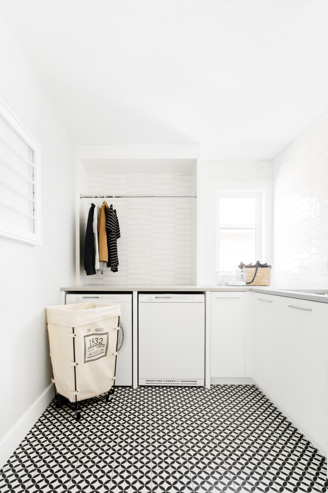 Design ideas for a contemporary l-shaped dedicated laundry room in Calgary with an undermount sink, flat-panel cabinets, white cabinets, white splashback, grey walls, a side-by-side washer and dryer, multi-coloured floor and grey benchtop.