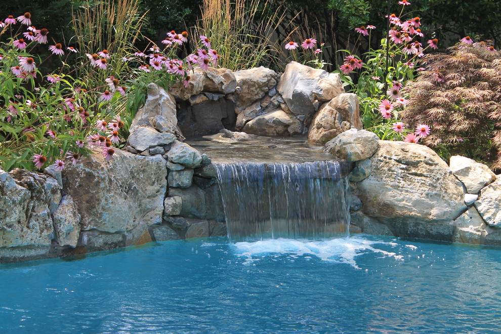 Design ideas for a mid-sized traditional backyard custom-shaped natural pool in New York with a water feature and natural stone pavers.