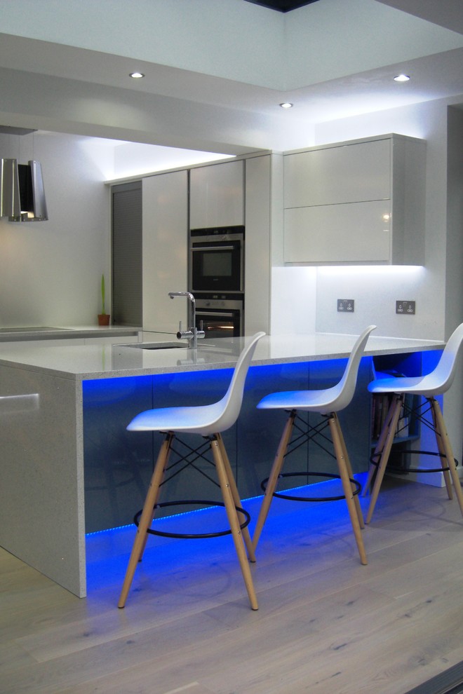 This is an example of a mid-sized contemporary open plan kitchen in West Midlands with white cabinets and quartzite benchtops.
