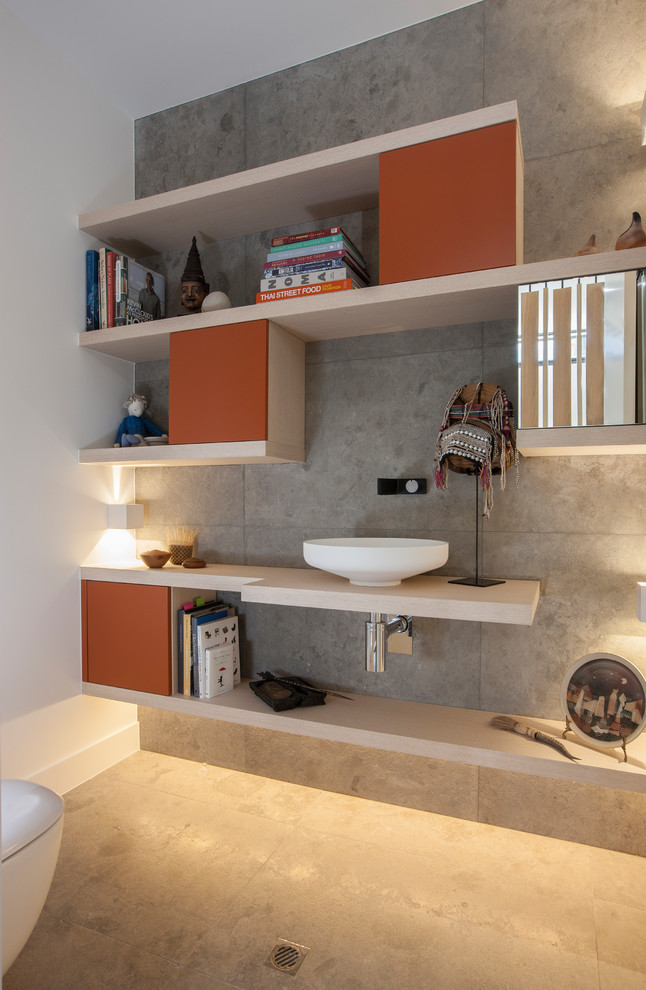 Photo of a small contemporary 3/4 bathroom in Adelaide with recessed-panel cabinets, orange cabinets, a wall-mount toilet, gray tile, limestone, white walls, limestone floors, laminate benchtops and grey floor.
