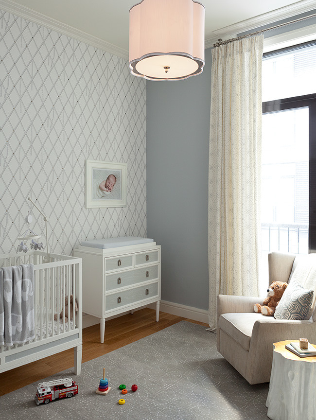This is an example of a mid-sized transitional nursery for boys in New York with blue walls and light hardwood floors.