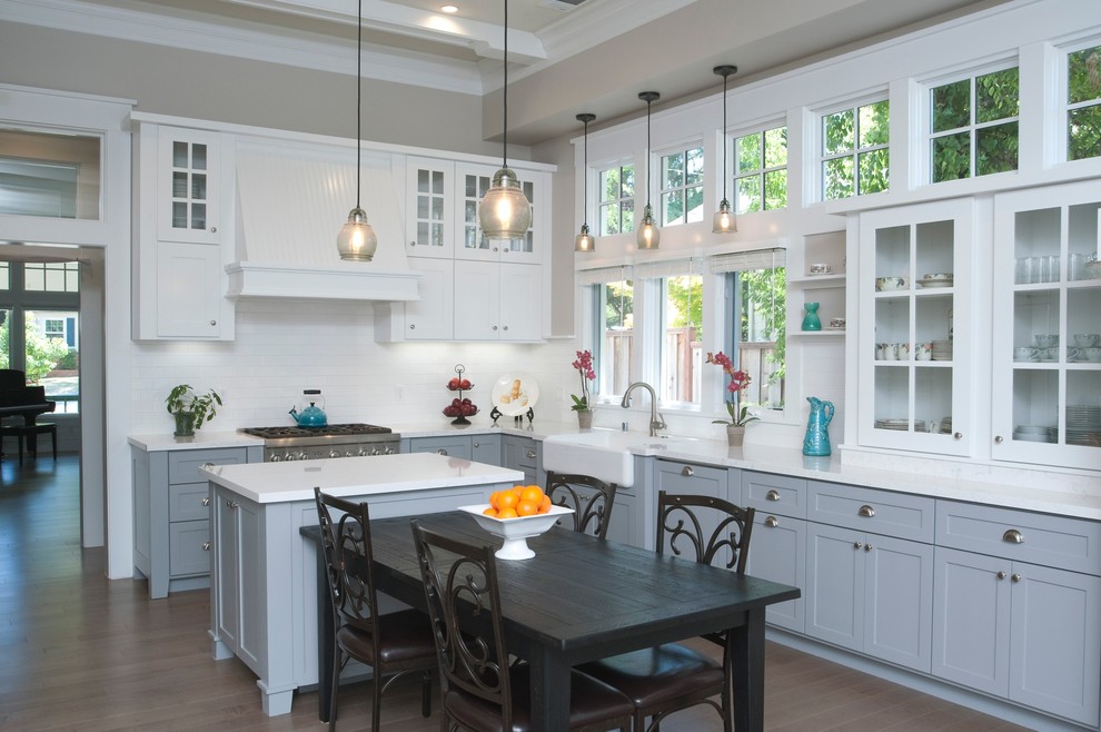 This is an example of a traditional eat-in kitchen in San Francisco with grey cabinets, white splashback and with island.