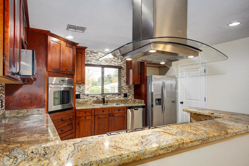 Example of a large transitional u-shaped travertine floor and beige floor enclosed kitchen design in Phoenix with a drop-in sink, shaker cabinets, dark wood cabinets, granite countertops, multicolored backsplash, matchstick tile backsplash, stainless steel appliances, a peninsula and brown countertops