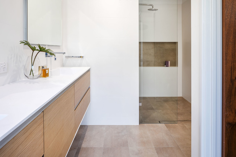This is an example of a mid-sized contemporary master bathroom in Perth with light wood cabinets, white tile, white walls, ceramic floors, an integrated sink, solid surface benchtops, beige floor and a hinged shower door.