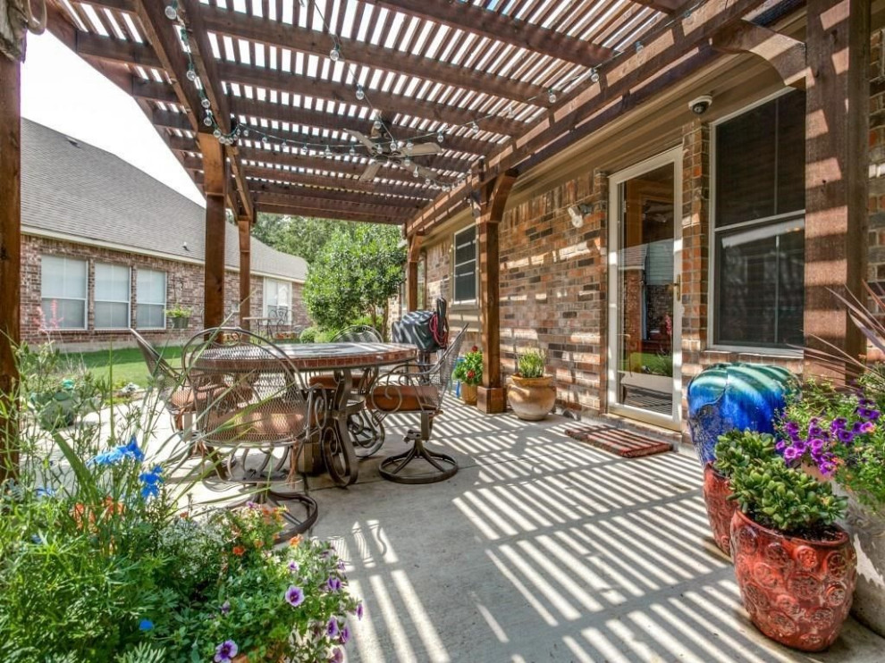 Inspiration for a mid-sized traditional backyard patio in Dallas with natural stone pavers and a pergola.