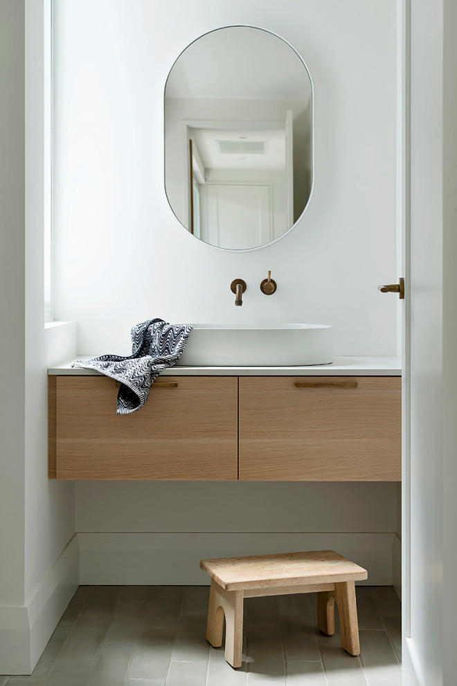 This is an example of a small contemporary powder room in Perth with medium wood cabinets, white walls, cement tiles, engineered quartz benchtops, beige floor, a floating vanity, flat-panel cabinets, a vessel sink and white benchtops.