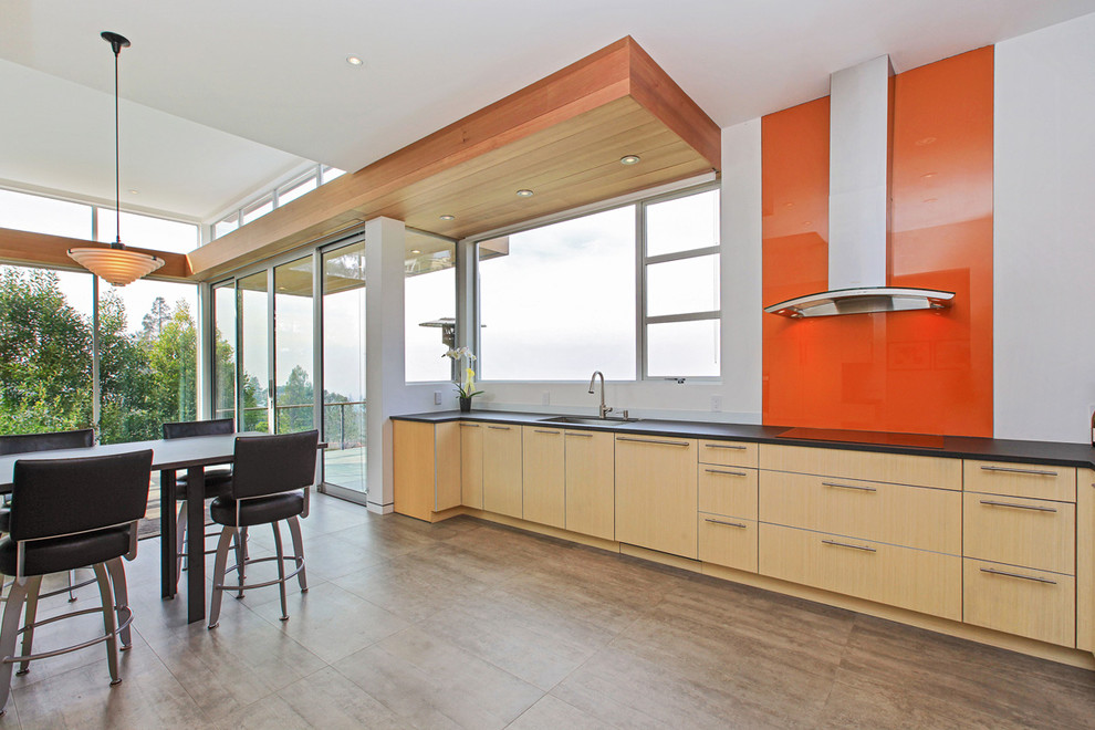 Inspiration for a large contemporary u-shaped open plan kitchen in San Francisco with an undermount sink, flat-panel cabinets, light wood cabinets, quartz benchtops, orange splashback, glass sheet splashback, stainless steel appliances and porcelain floors.