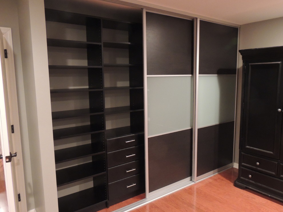 Photo of a mid-sized contemporary gender-neutral built-in wardrobe in Philadelphia with flat-panel cabinets, dark wood cabinets and medium hardwood floors.