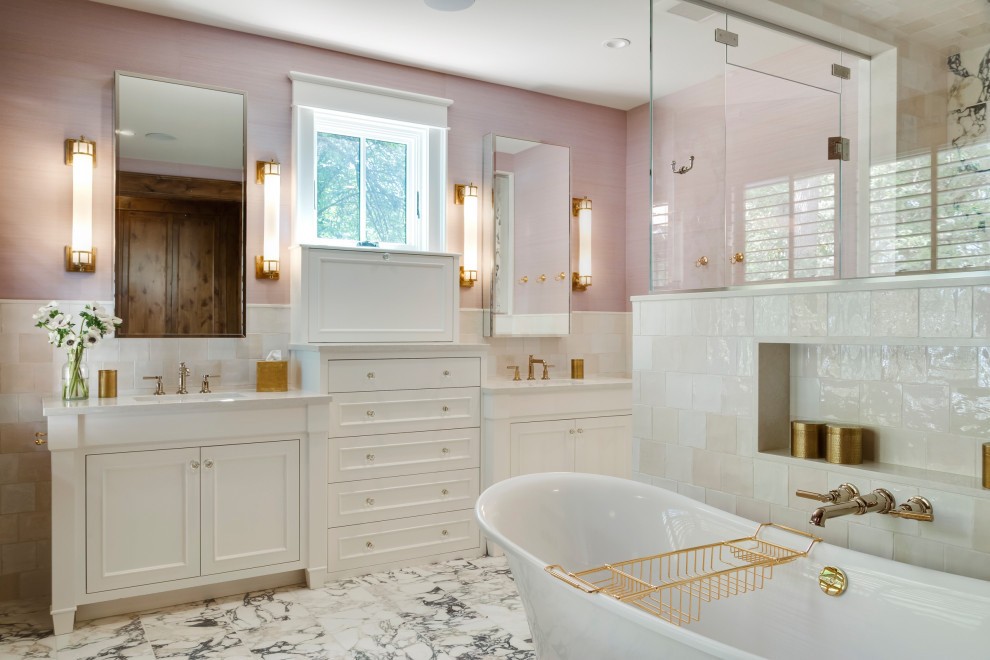 This is an example of a large rustic ensuite bathroom in Minneapolis with recessed-panel cabinets, white cabinets, a freestanding bath, a corner shower, a one-piece toilet, white tiles, ceramic tiles, pink walls, ceramic flooring, a submerged sink, quartz worktops, multi-coloured floors, a hinged door, white worktops, an enclosed toilet, double sinks, a built in vanity unit and wallpapered walls.