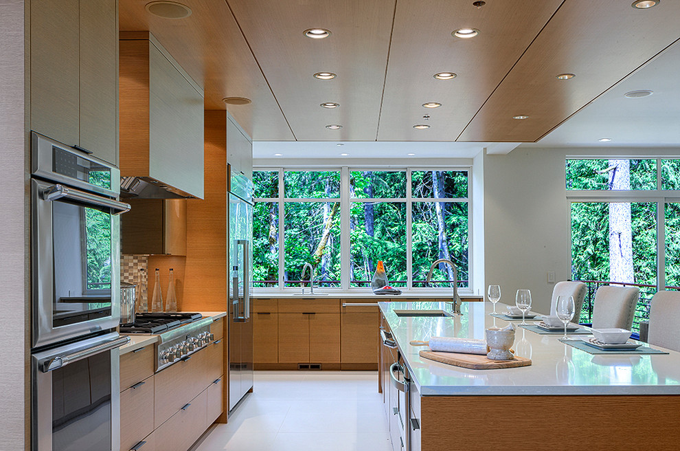 This is an example of a contemporary open plan kitchen in Seattle with a drop-in sink, flat-panel cabinets, medium wood cabinets, beige splashback, stainless steel appliances and with island.
