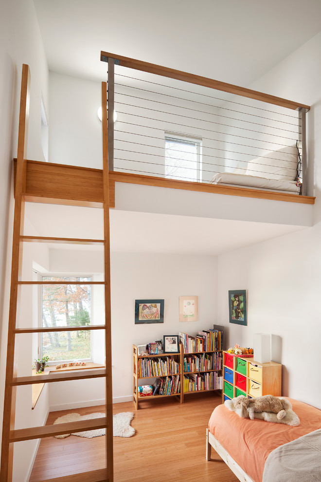 This is an example of a contemporary gender-neutral kids' bedroom in Portland Maine with white walls and medium hardwood floors.
