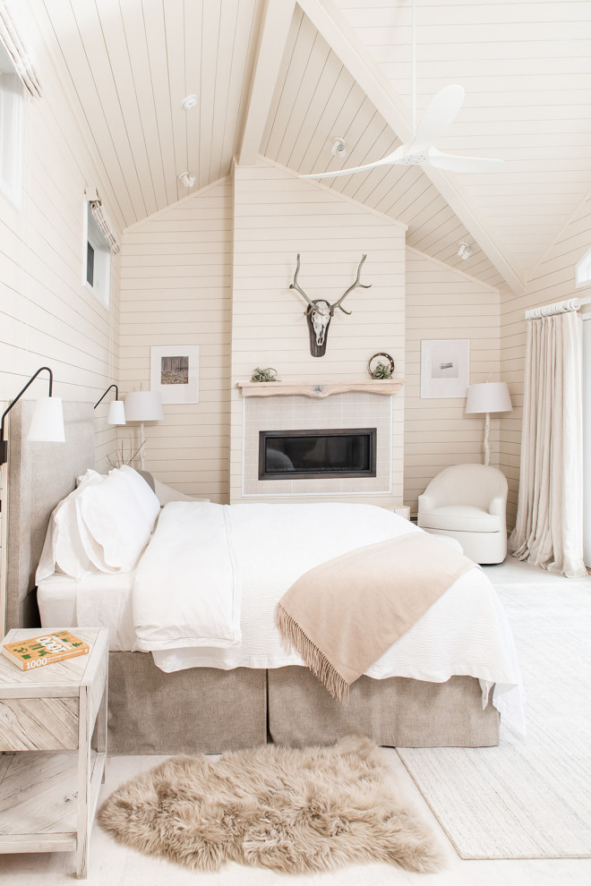 Cette photo montre une grande chambre parentale bord de mer avec un mur beige, parquet clair, une cheminée standard, un manteau de cheminée en lambris de bois, un sol blanc, un plafond en lambris de bois et du lambris de bois.