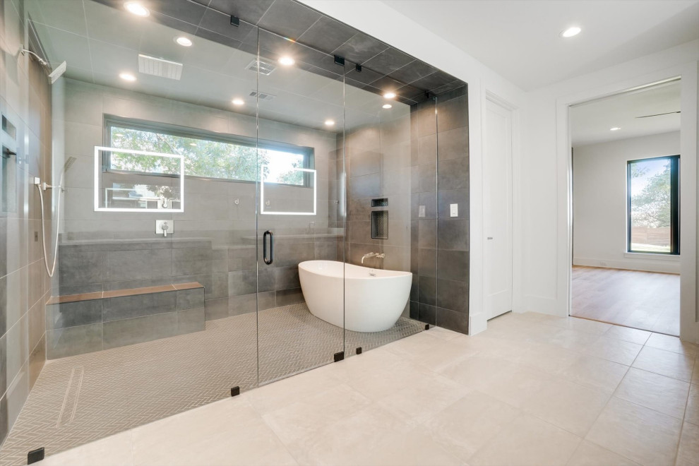 На фото: большая главная ванная комната в стиле модернизм с плоскими фасадами, серыми фасадами, отдельно стоящей ванной, душем в нише, унитазом-моноблоком, бежевой плиткой, керамической плиткой, белыми стенами, полом из известняка, врезной раковиной, столешницей из известняка, бежевым полом, душем с распашными дверями, бежевой столешницей, сиденьем для душа, тумбой под две раковины и подвесной тумбой с
