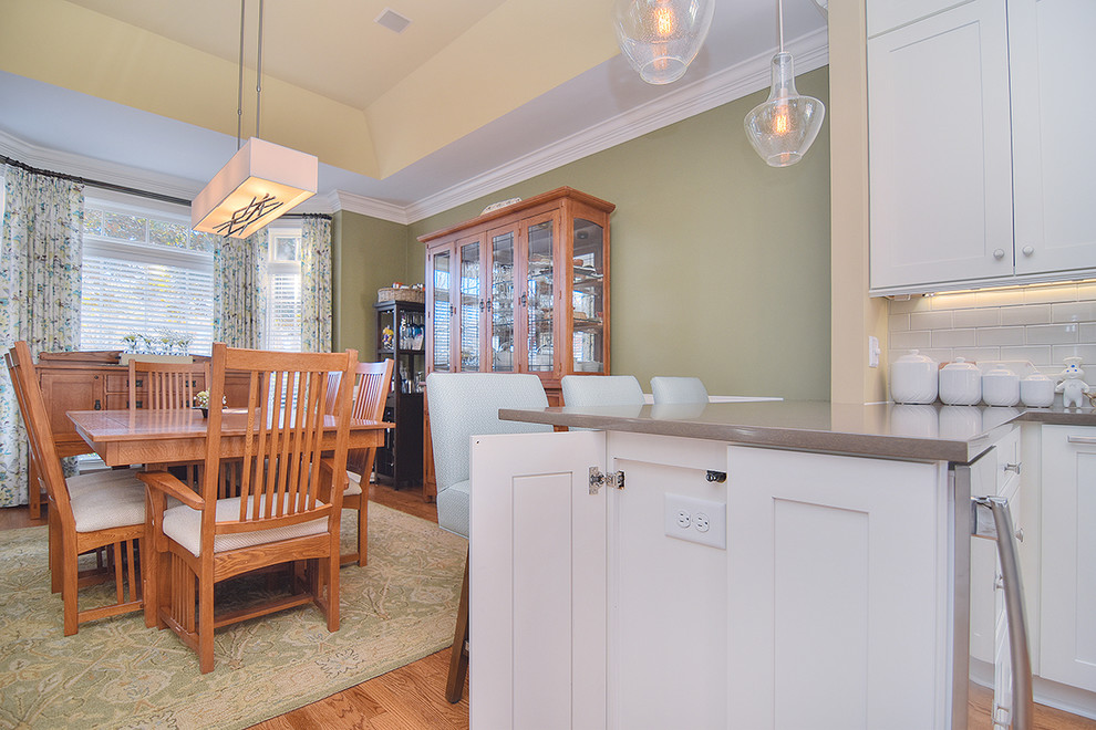 Enclosed kitchen - large transitional u-shaped light wood floor and brown floor enclosed kitchen idea in Charlotte with a farmhouse sink, shaker cabinets, white cabinets, quartz countertops, white backsplash, subway tile backsplash, stainless steel appliances and a peninsula