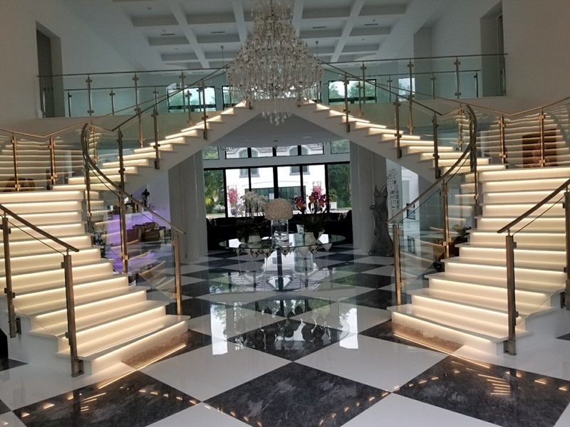 This is an example of an expansive modern painted wood curved staircase in Miami with painted wood risers and glass railing.