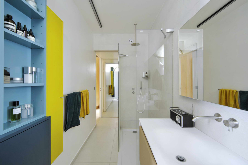 Photo of a mid-sized contemporary master bathroom in Paris with flat-panel cabinets, blue cabinets, a curbless shower, a wall-mount toilet, gray tile, cement tile, grey walls, ceramic floors, a console sink and solid surface benchtops.