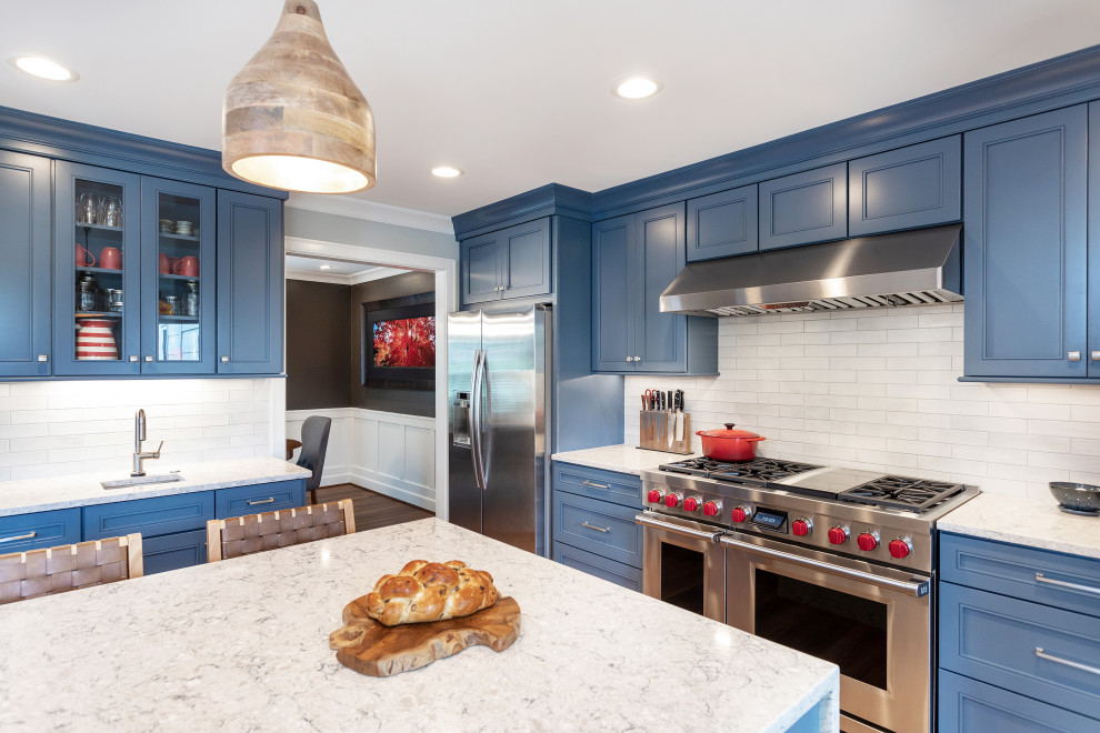 This is an example of a transitional kitchen in Raleigh with recessed-panel cabinets, blue cabinets, quartz benchtops, white splashback, subway tile splashback, stainless steel appliances, vinyl floors and yellow benchtop.