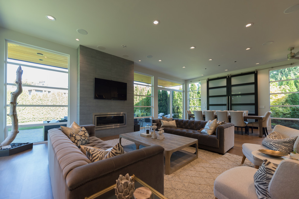 Large contemporary formal open concept living room in Vancouver with white walls, medium hardwood floors, a standard fireplace and a wall-mounted tv.