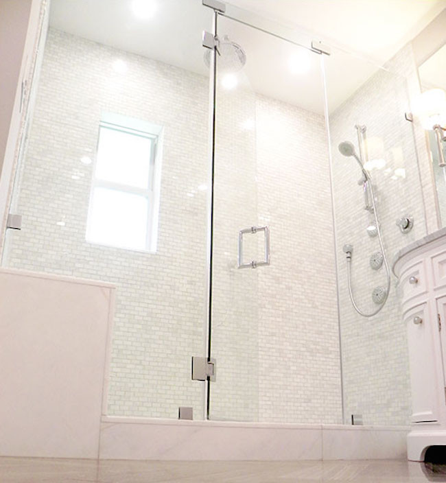 This is an example of a mid-sized contemporary 3/4 bathroom in Phoenix with recessed-panel cabinets, white cabinets, an alcove shower, gray tile, white tile, stone tile, white walls, medium hardwood floors, an undermount sink, marble benchtops, brown floor and a hinged shower door.