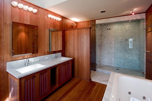 Expansive contemporary master bathroom in Portland Maine with an undermount sink, beaded inset cabinets, dark wood cabinets, marble benchtops, a drop-in tub, a double shower, white tile, stone slab, brown walls and dark hardwood floors.