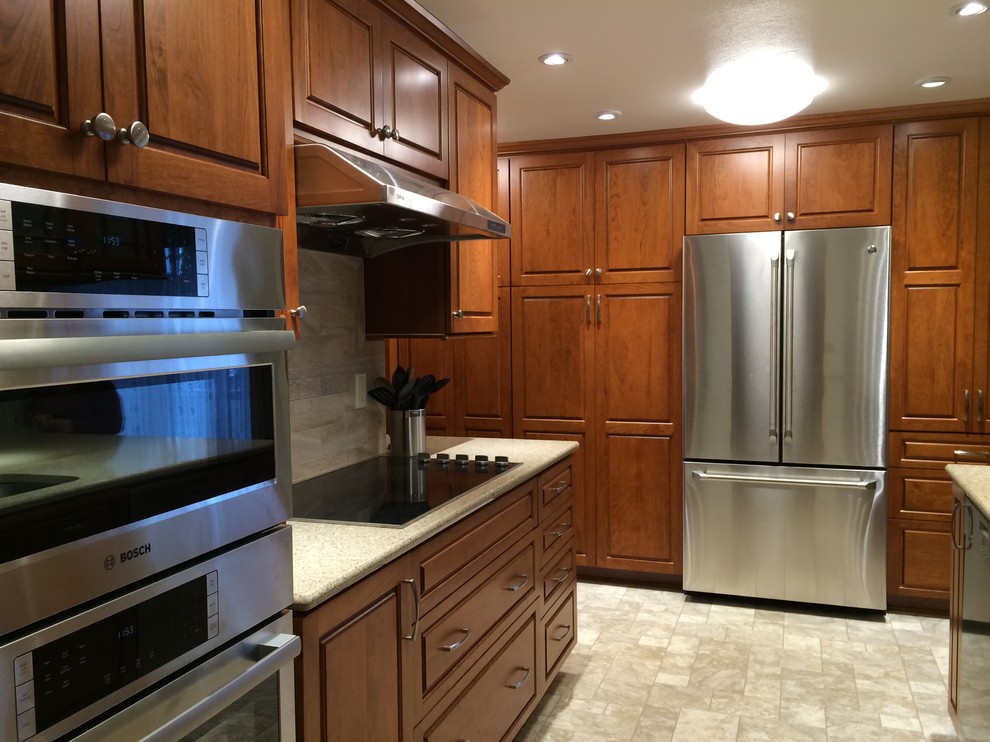 Example of a mid-sized transitional linoleum floor kitchen design in Seattle with an undermount sink, raised-panel cabinets, medium tone wood cabinets, quartzite countertops, beige backsplash, ceramic backsplash and stainless steel appliances